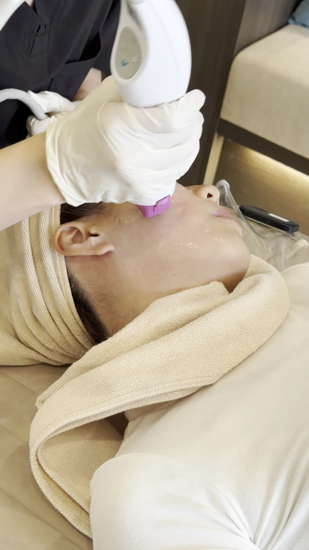 Thermage handpiece placed close to a reclining persons face
