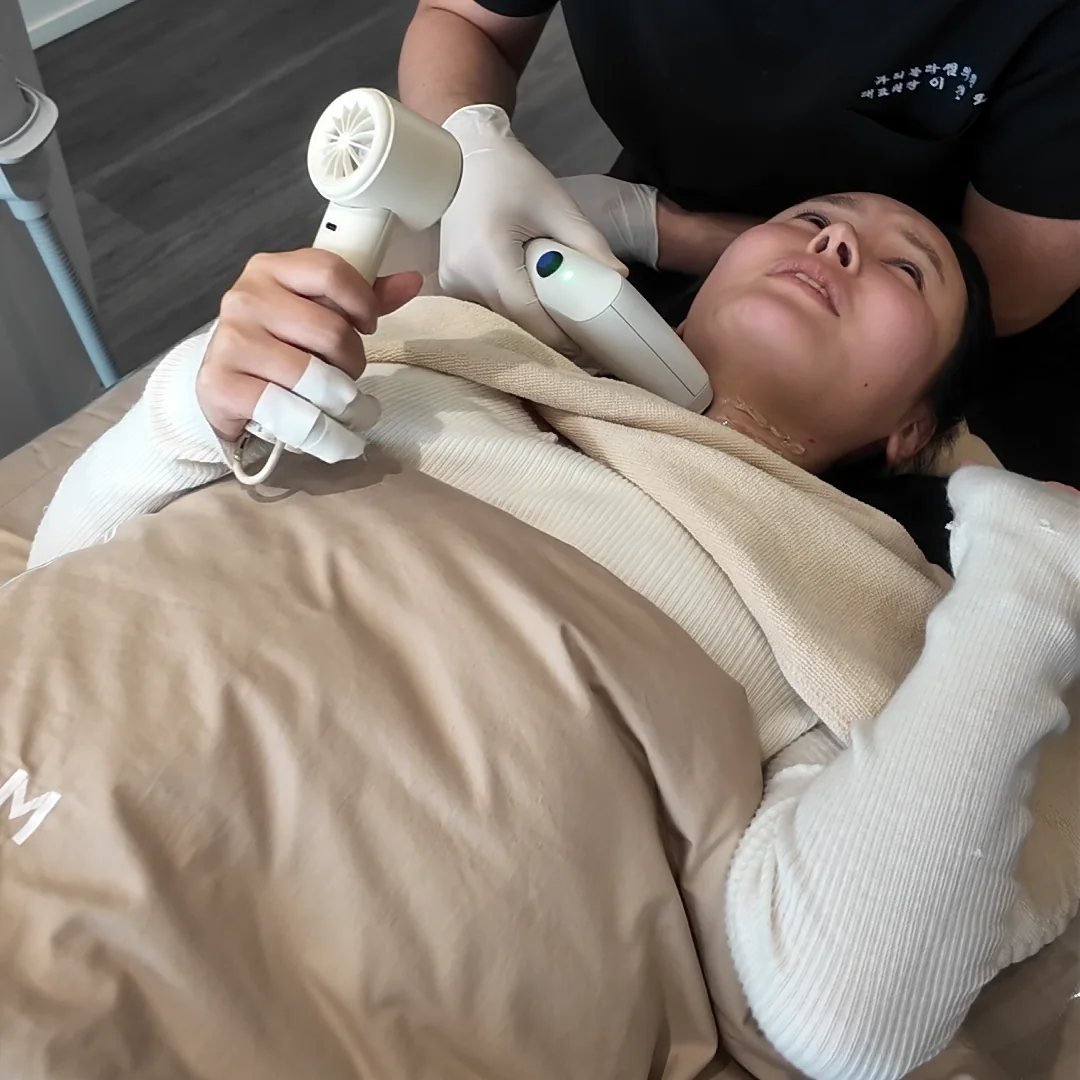 Sofwave handpiece contacting the front of a patient’s neck during treatment
