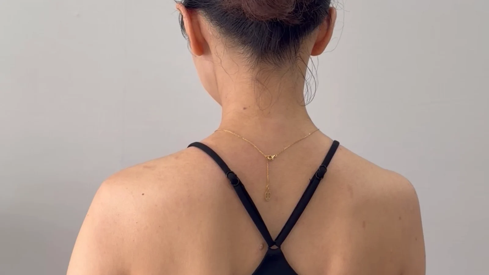 The back and shoulders of a person in a black sleeveless top in a clinic room.
