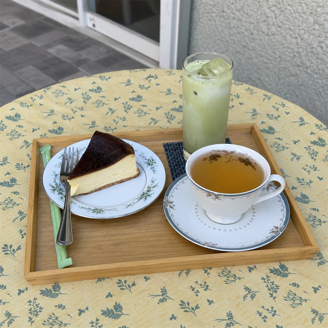 Wooden tray with a slice of cake, tea and a pale green iced drink