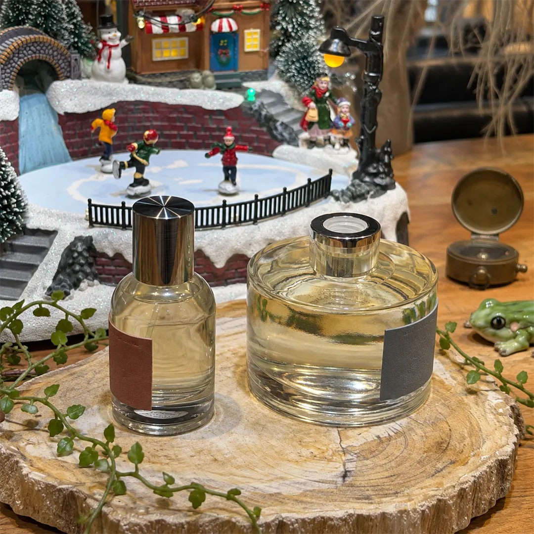 Finished perfume bottle and diffuser bottle on a wooden slice with a small winter miniature behind