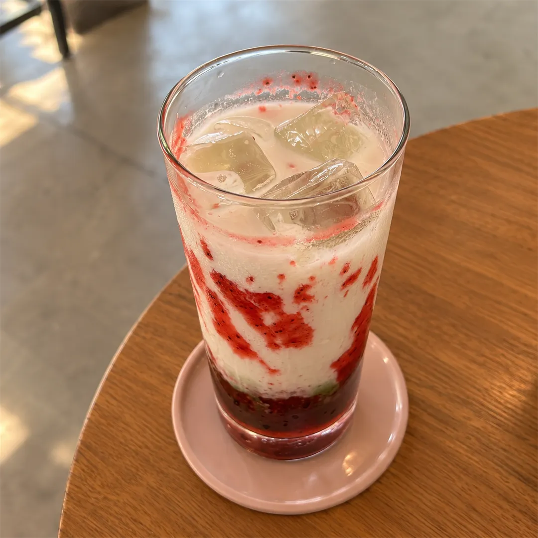 Close-up of a glass drink with red sauce and white cream