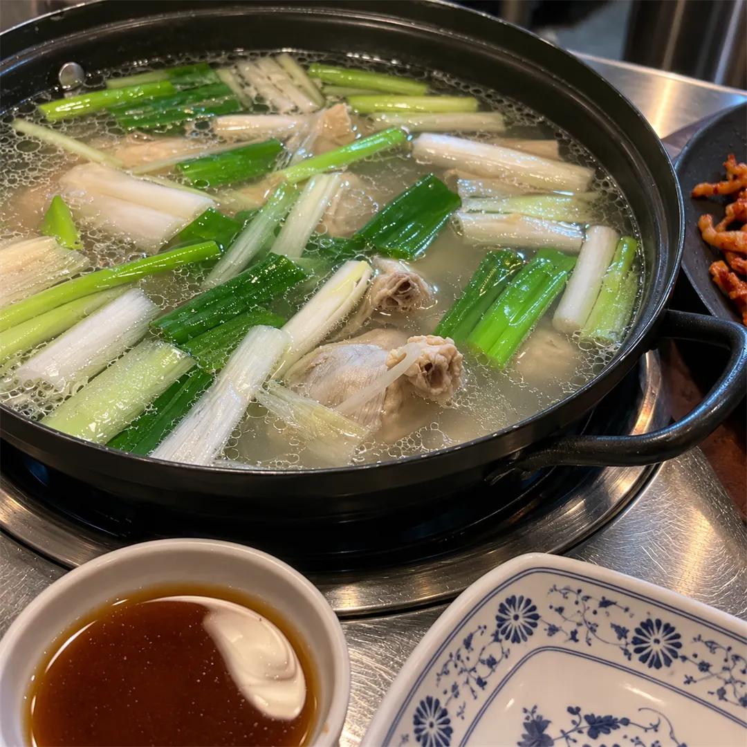 ภาพใกล้ของหม้อน้ำซุปใสที่มีต้นหอมและชิ้นไก่