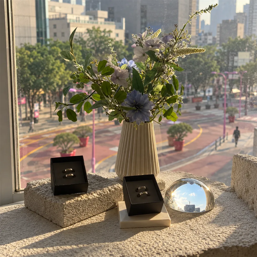Stone window shelf with a vase, a ring box and a glass dome in warm sunlight