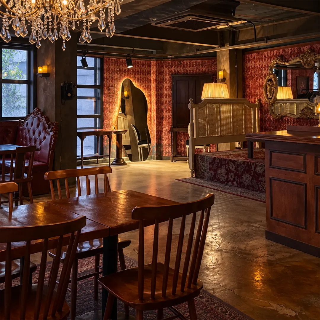 Room with red patterned wallpaper, a chandelier, mirrors and a daybed-style seat with a wooden table