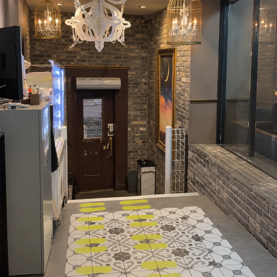 Brick stairwell entrance with a wooden door, gold frame and patterned tiles