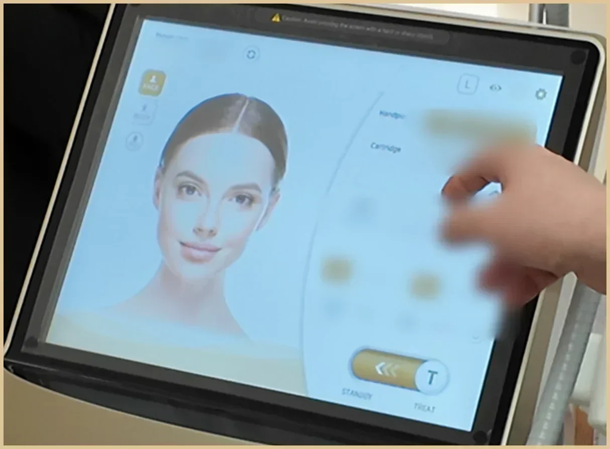 Hand touching the touchscreen of a demo console that shows an illustrated face, settings values blurred