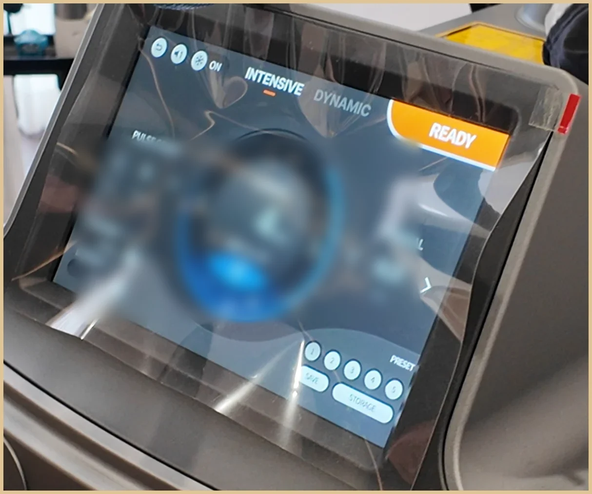 Close-up of a laser console touchscreen with the Intensive and Dynamic tabs and a Ready indicator, settings values blurred