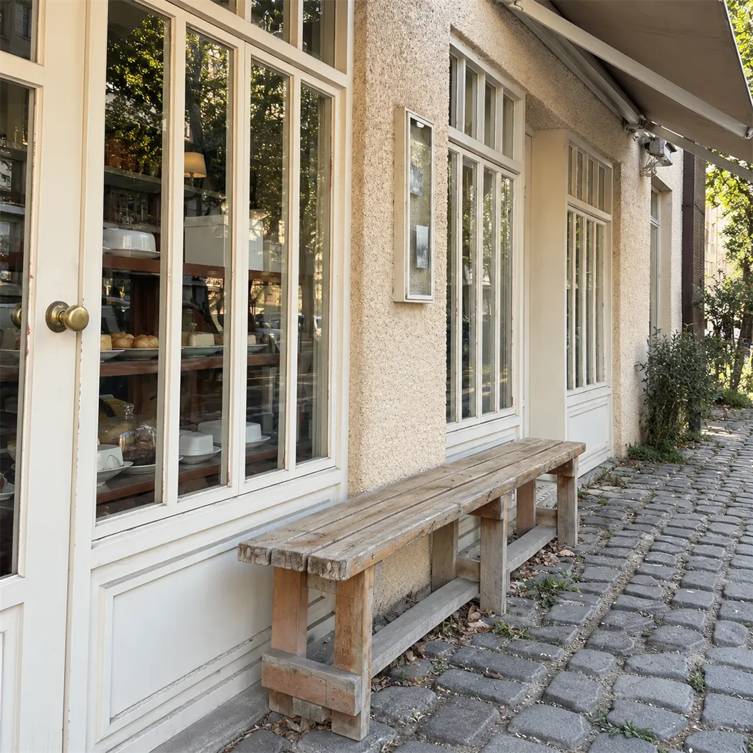 Wooden bench and white lattice window beside a shop window displaying baked goods