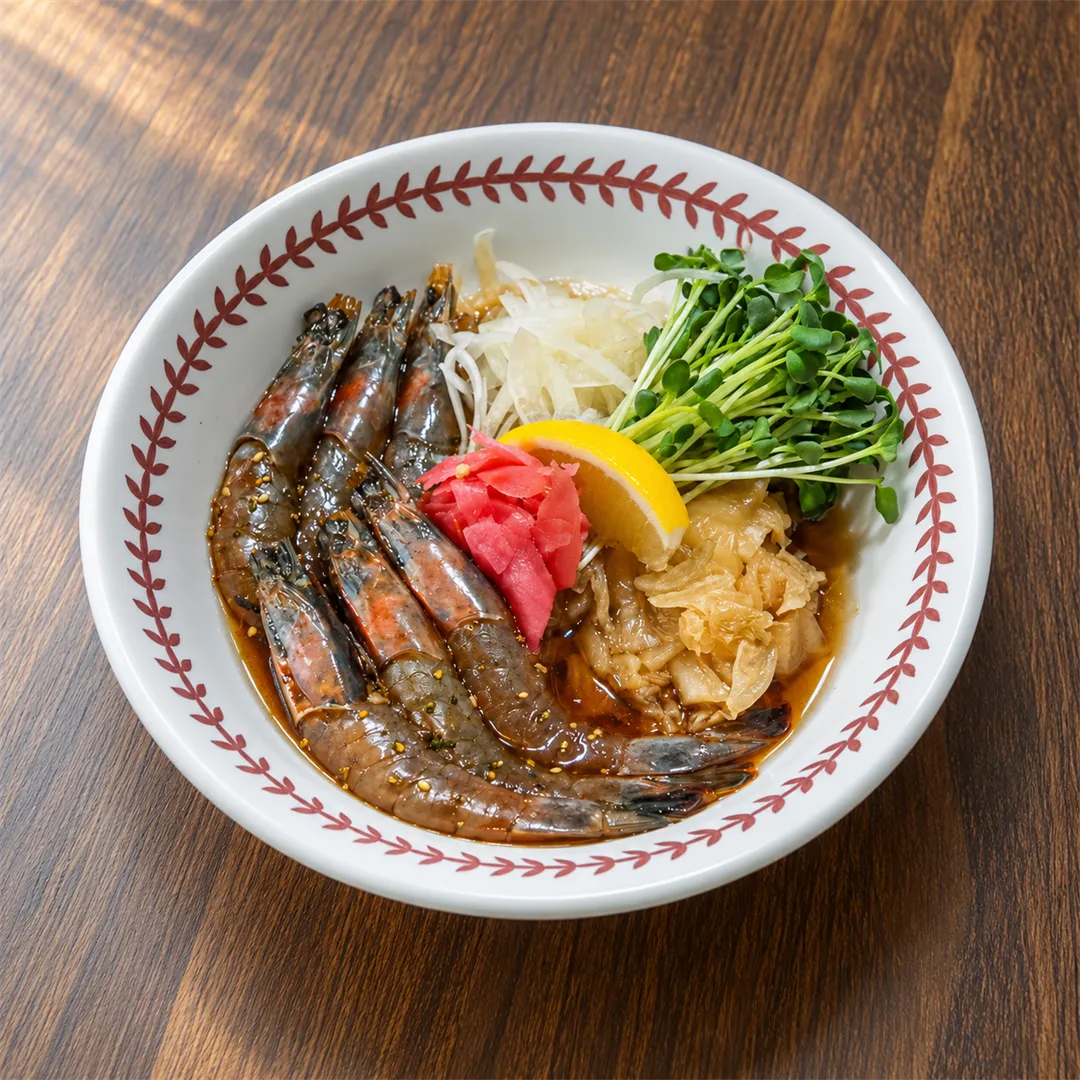 Soy-marinated shrimp with sliced onion, sprouts and lemon in a white bowl