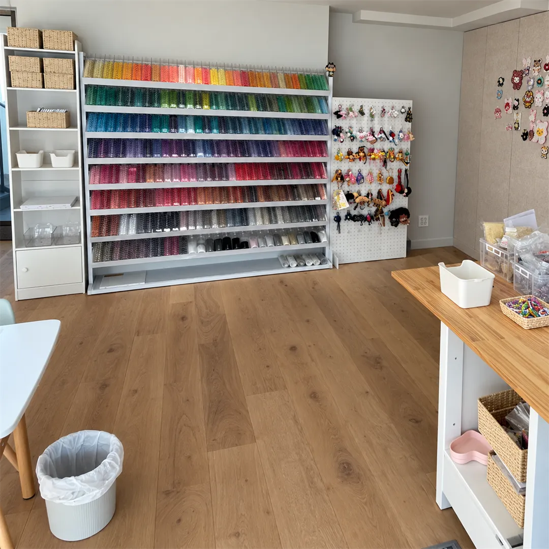Wall shelf of clear jars holding beads sorted by color, next to a white pegboard