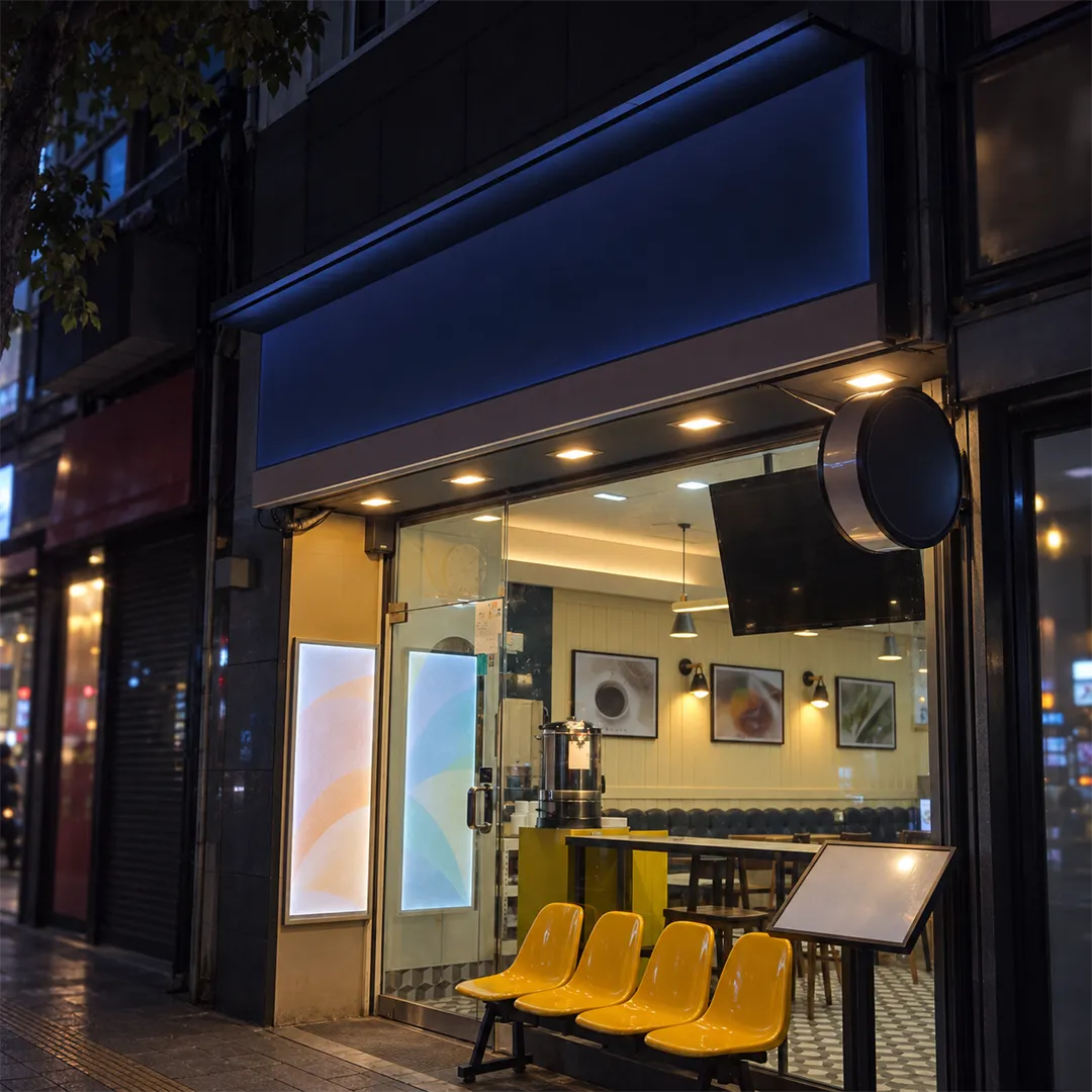 Shop front at night with a navy sign and warm light through the glass
