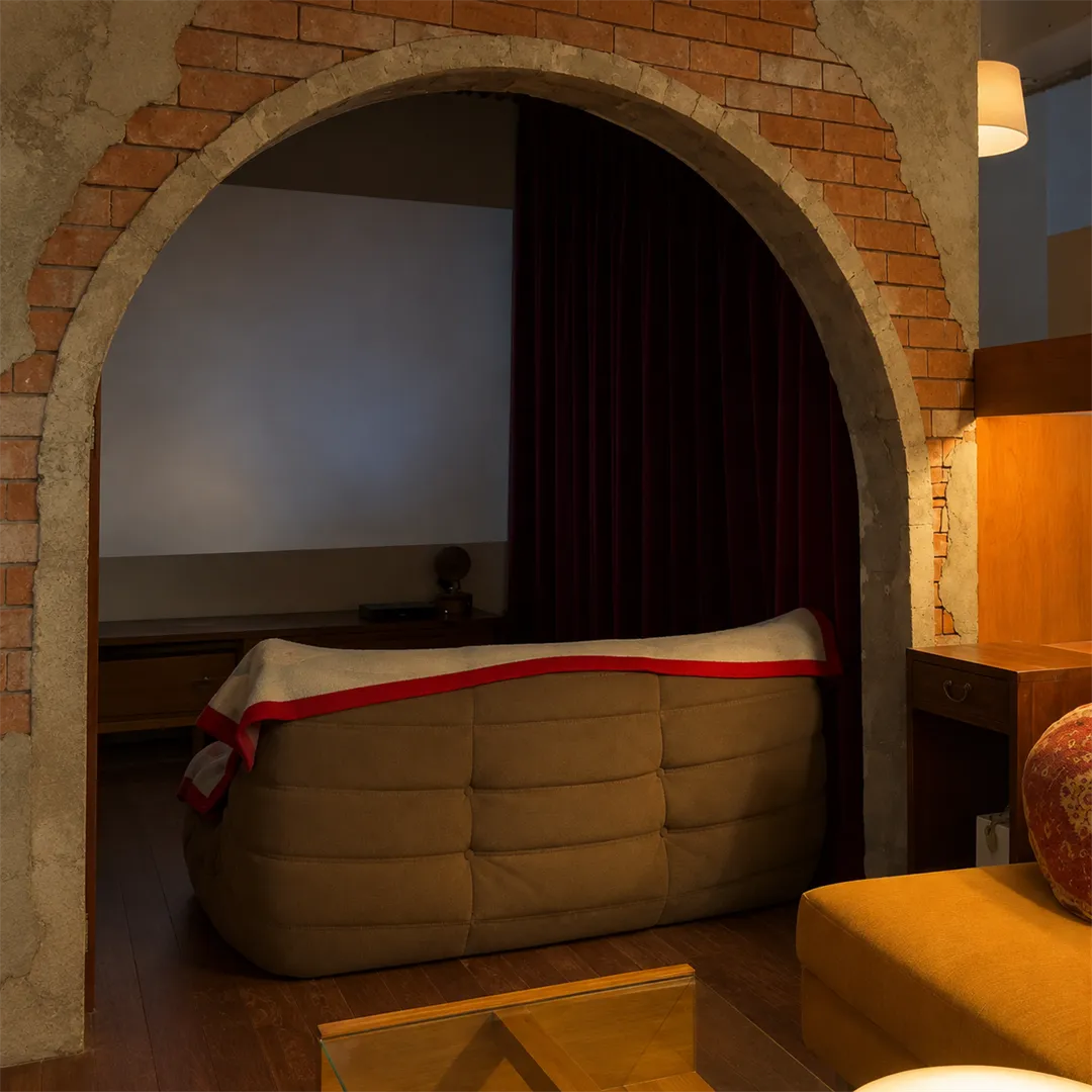 Brick arch with a brown sofa, red curtain and a grey projection wall inside