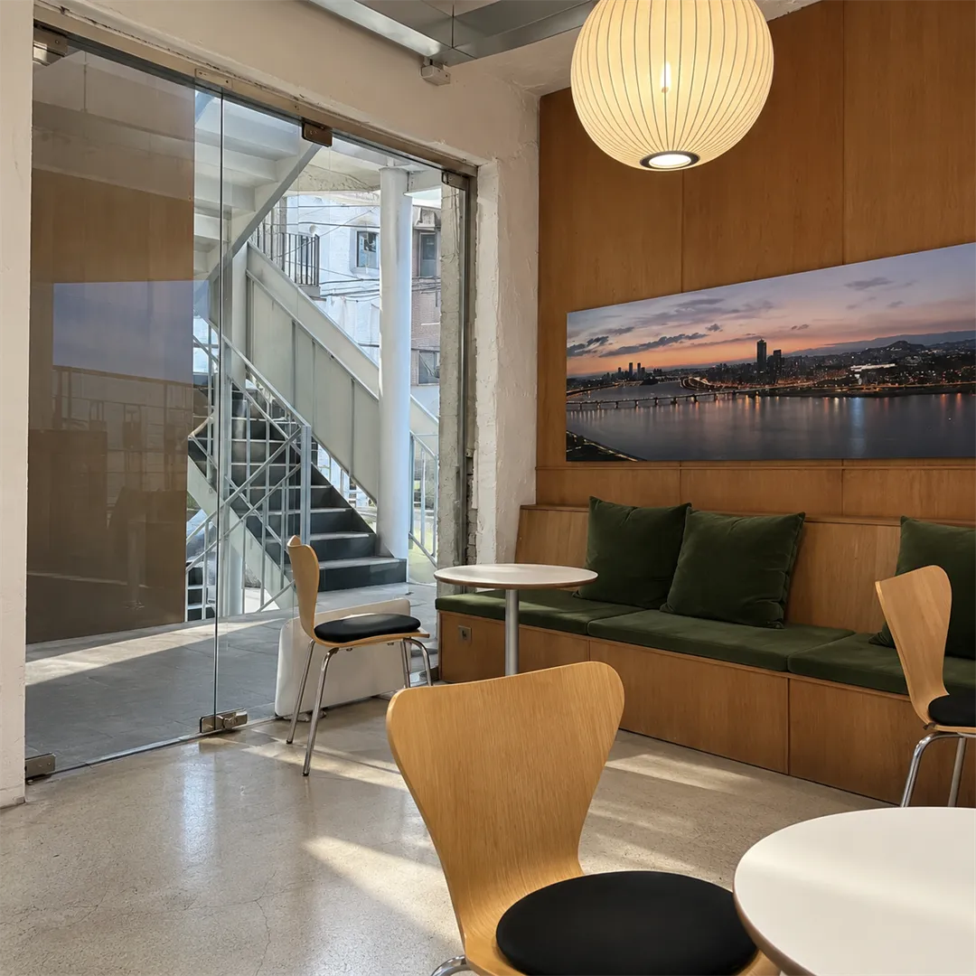 Green bench seating beside a glass door, a wooden wall panel with a night-view photo and round pendant lights