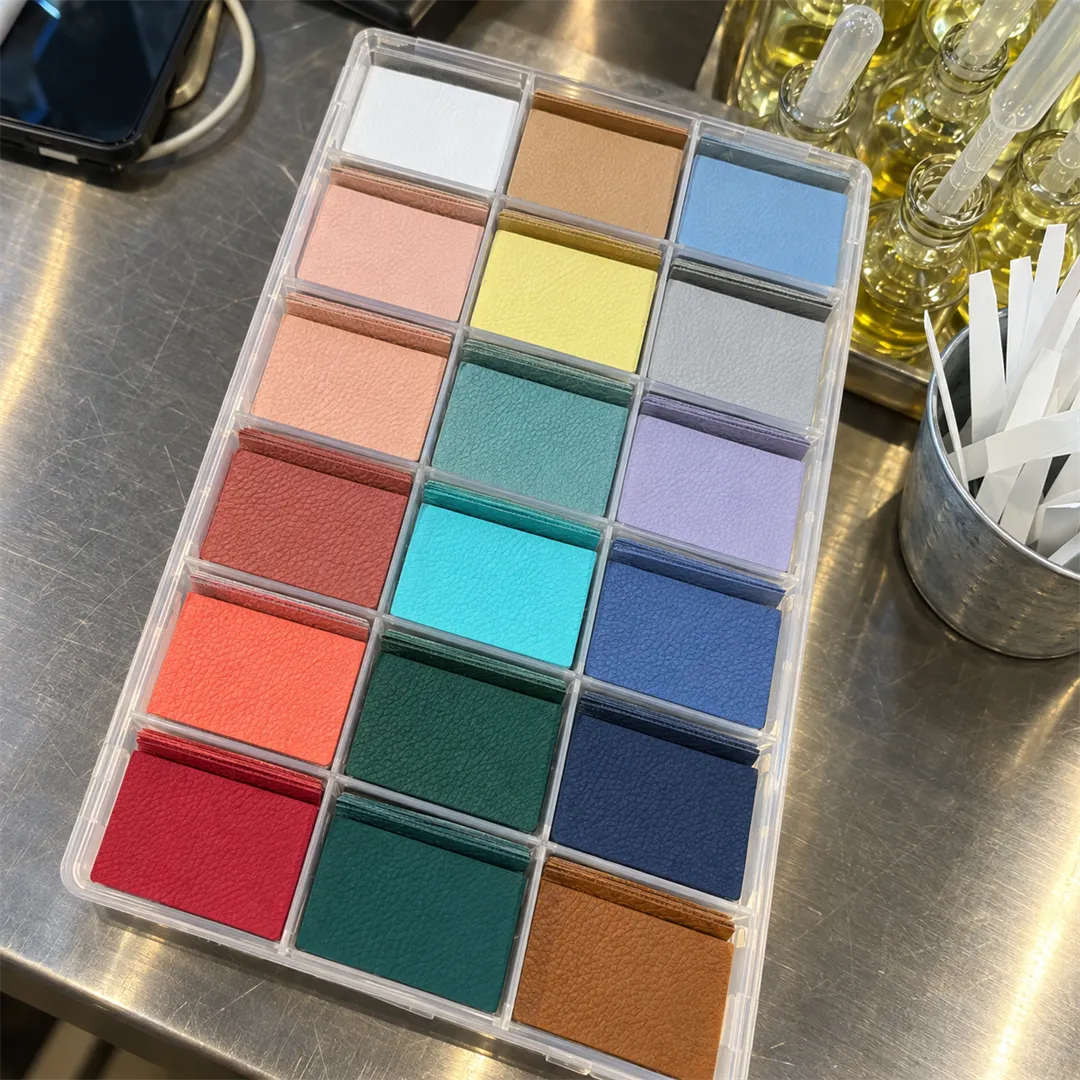 Clear divided tray holding leather label pieces in several colors, with a bottle and a white stick holder at the right