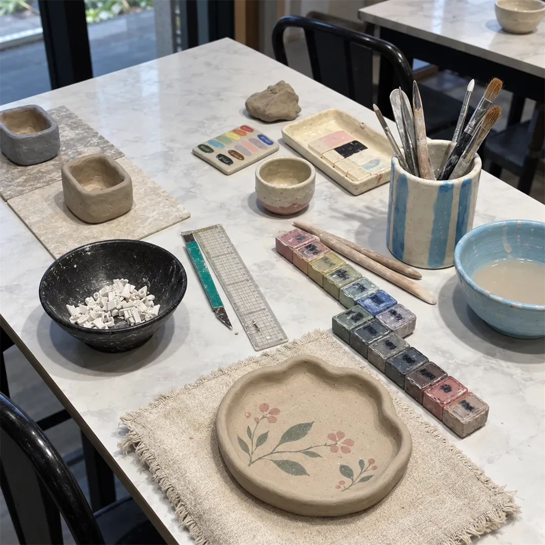 White marble-pattern work table with a plate painted with plant motifs, a palette, a brush holder and clay tools