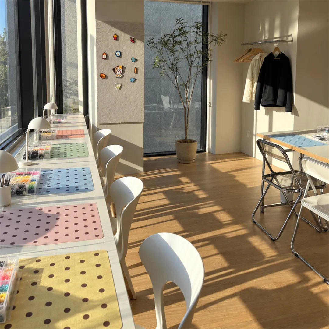 Long white work counter along a window with colorful polka-dot mats, bead organizers and desk lamps