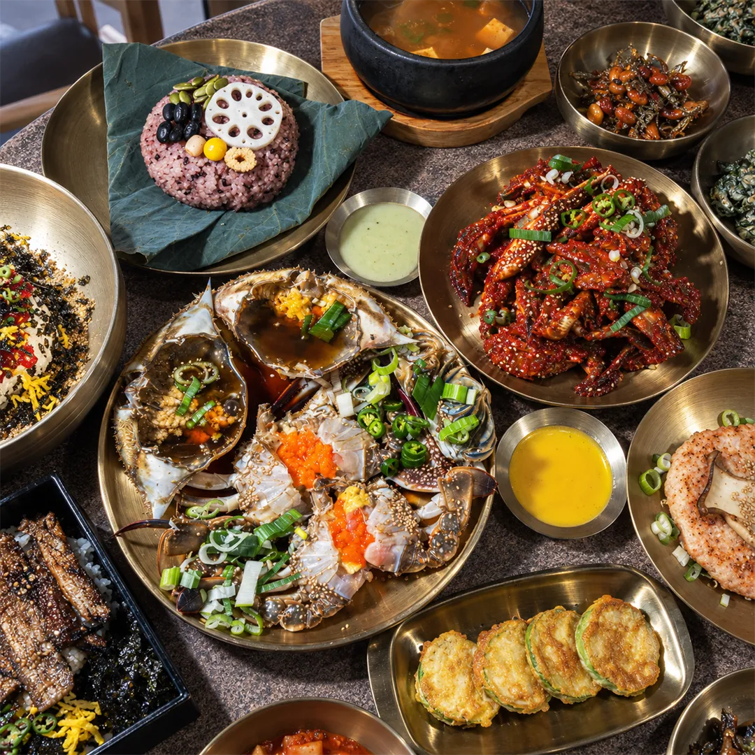 Soy-marinated crab, spicy crab and lotus-leaf rice with jeon and side dishes on brass plates