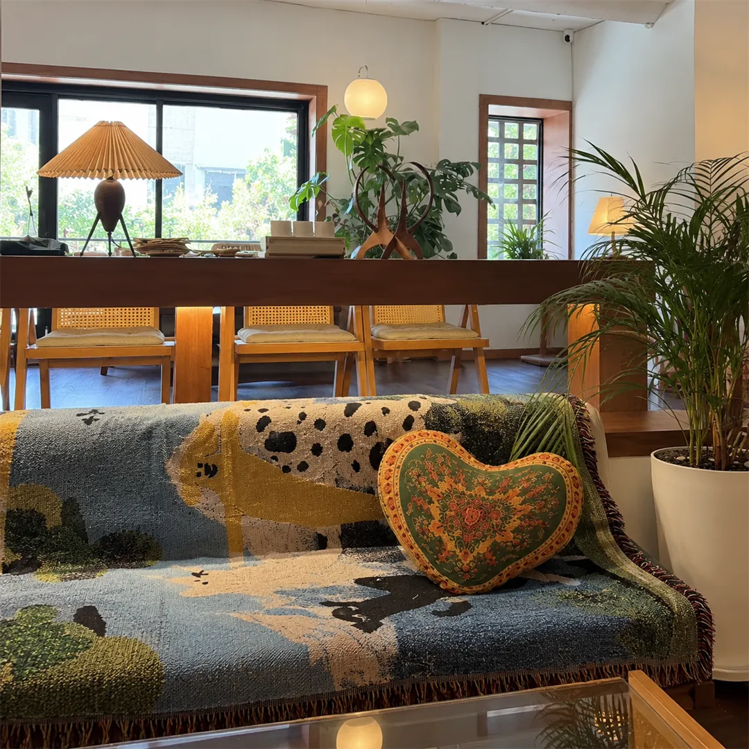 Patterned fabric sofa with heart cushions, a white plant pot and wooden window frames