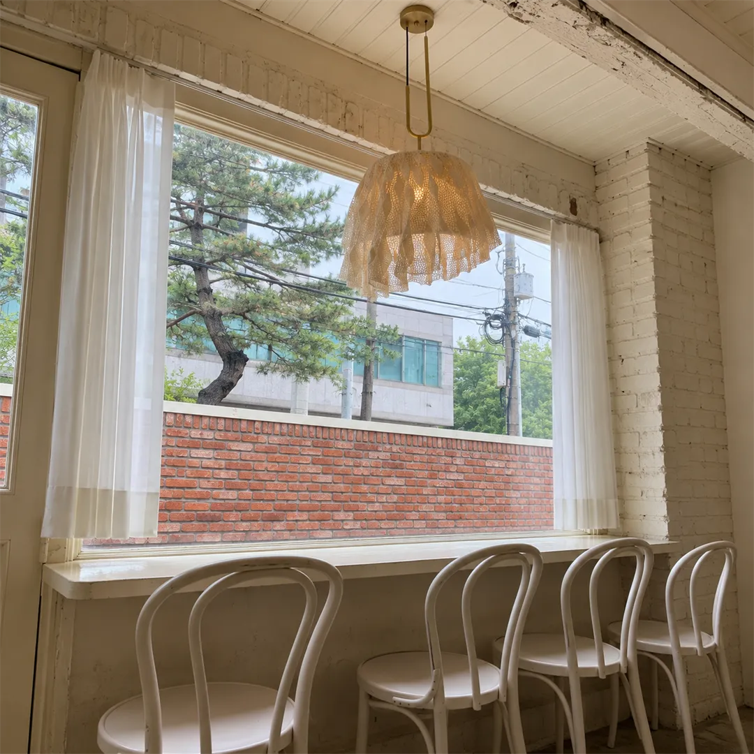 Window bar seating with white chairs and pendant lights inside the cafe