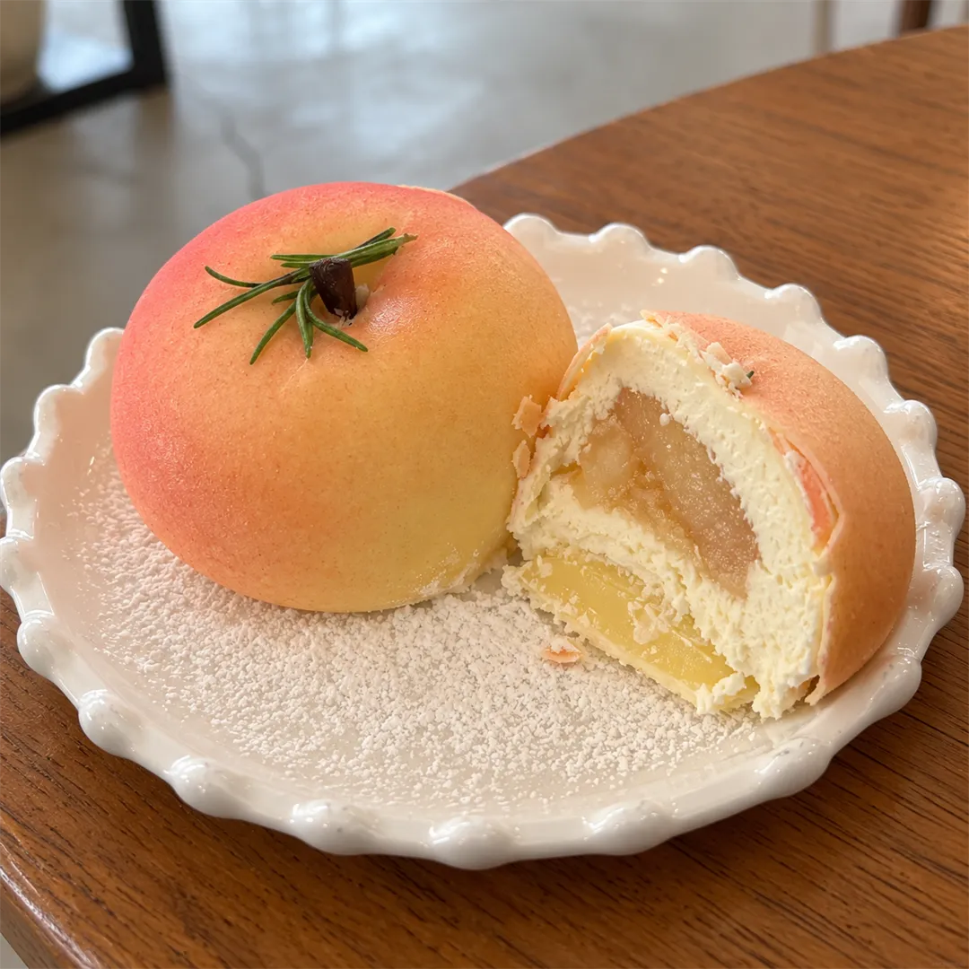 Peach-shaped dessert and its cross-section with a rosemary garnish
