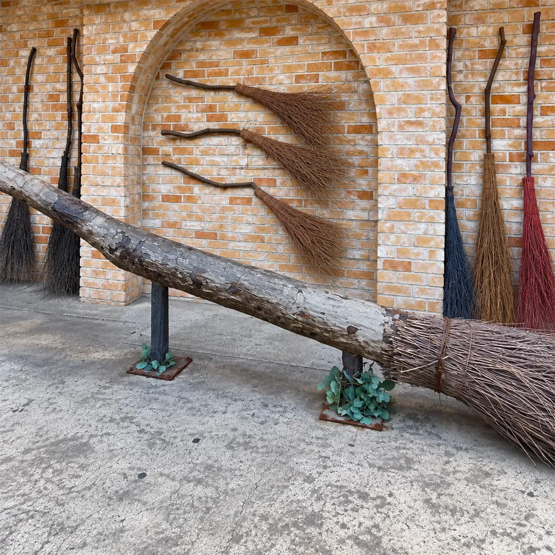 Brick arch entrance with a large broom installation and several colorful brooms against the wall