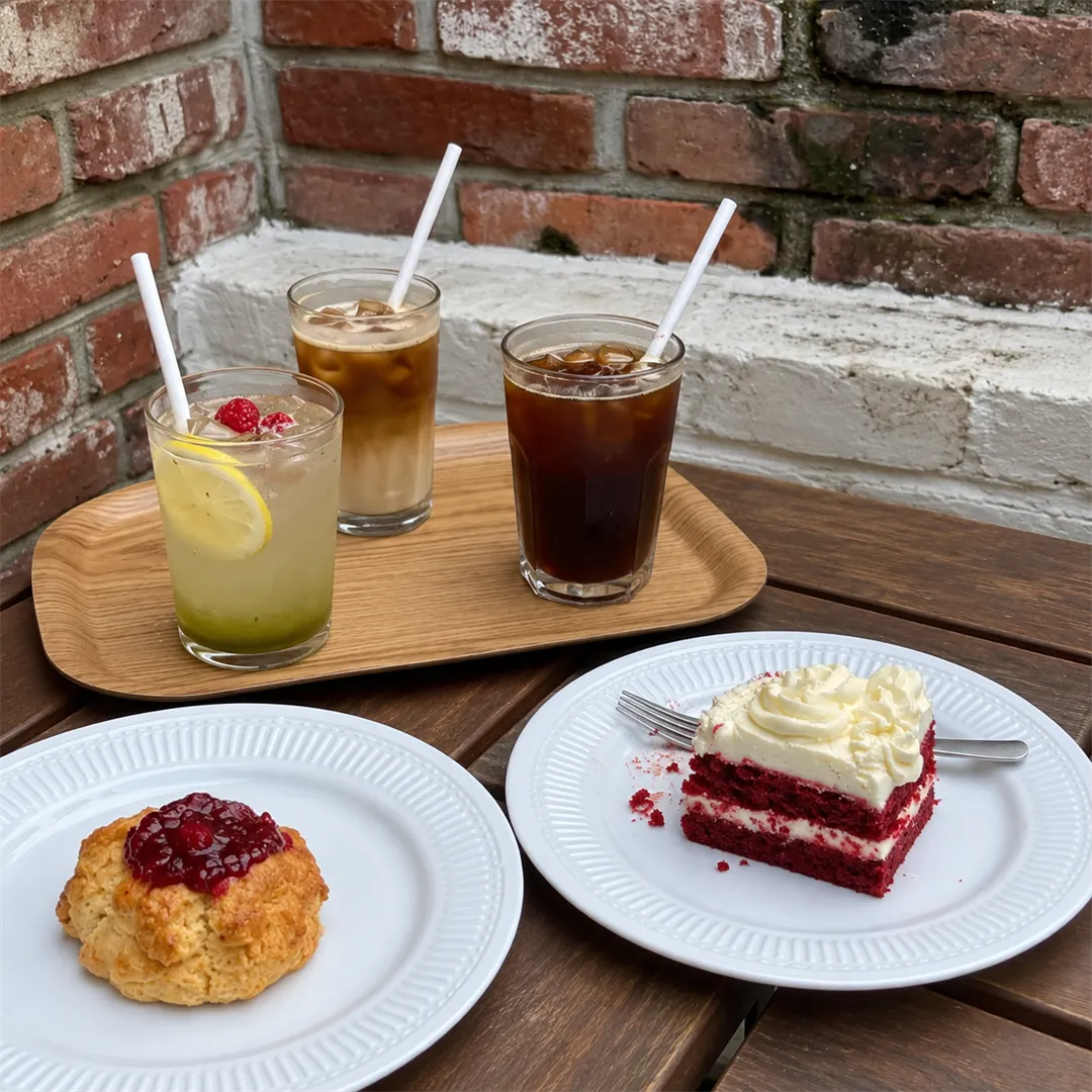 Terrace table with a tray holding a latte, black coffee, a cake and a scone