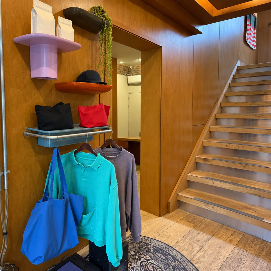 Wooden staircase beside shelves of hats, bags and clothing in a cafe
