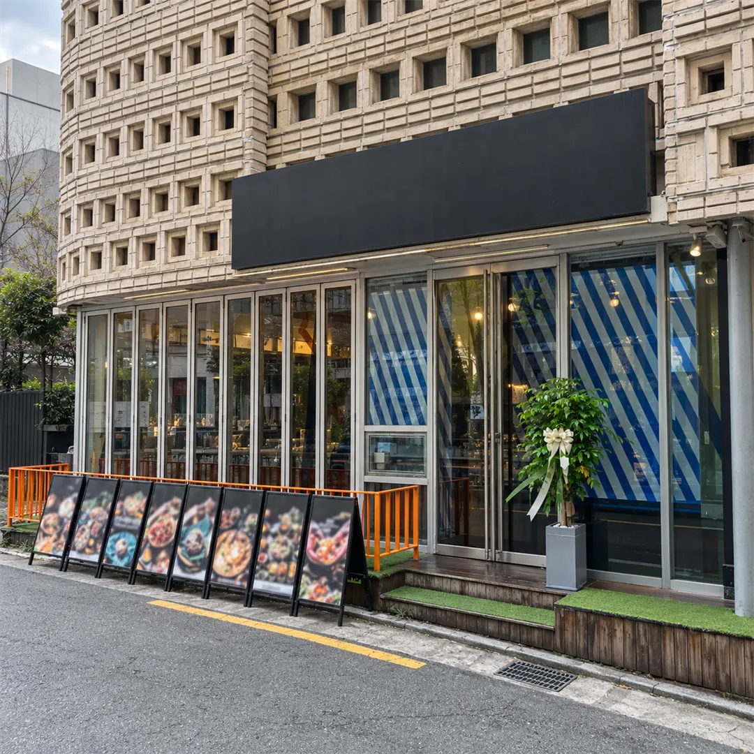 Building front with small square openings, blue striped windows, an orange railing and menu signs